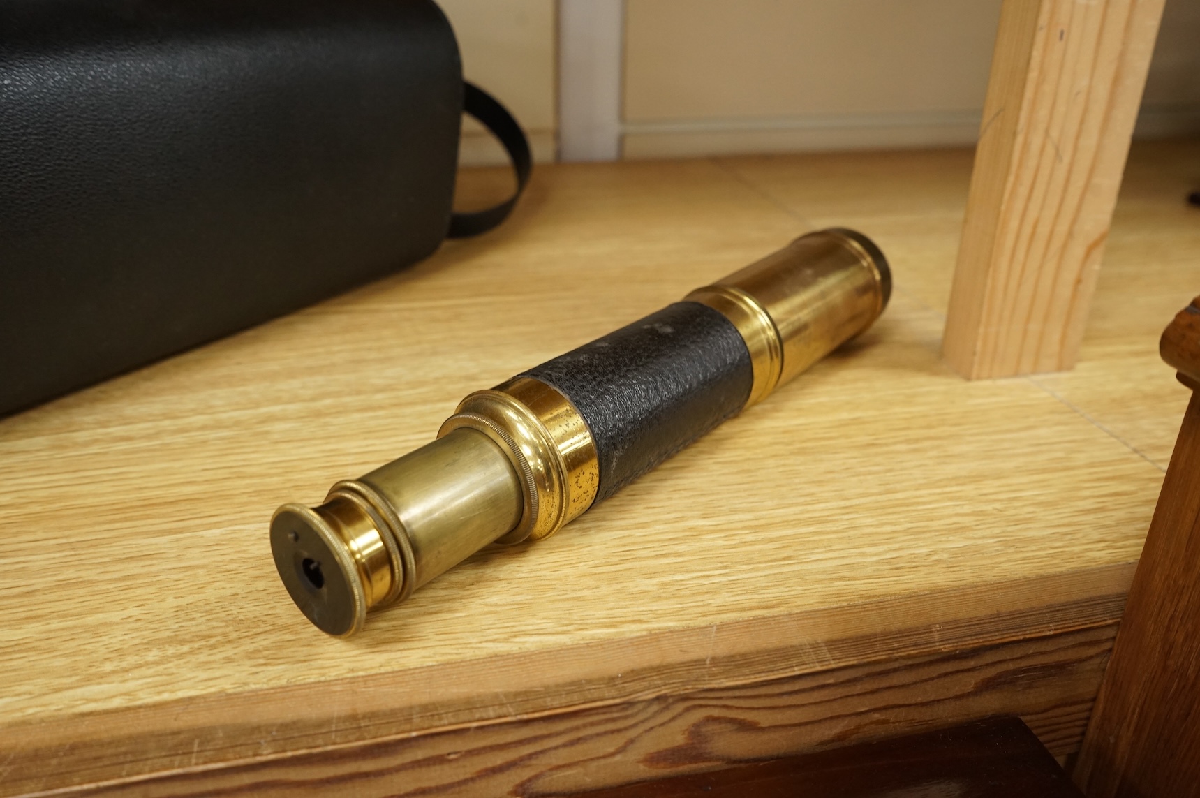 A late 19th/early 20th century three drawer brass telescope with leather covered grip, 59.5cm extended, 21cm when shut.